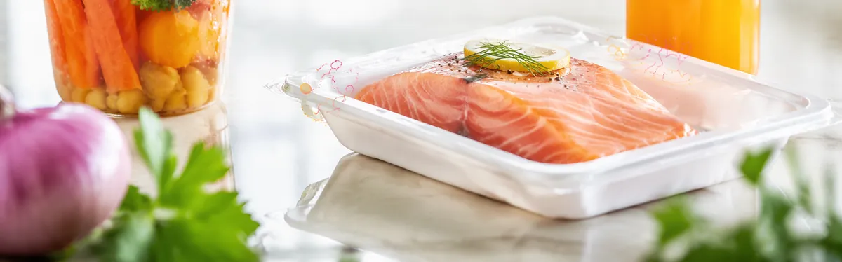 Packed salmon fillet in a sealed tray beside a vegetable cup and bottled juice, oxygen-sensitive packaged foods